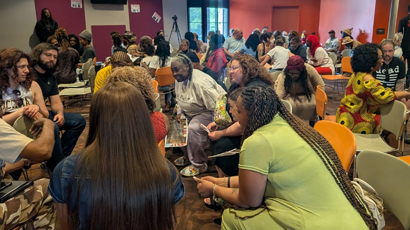 Community room full of diverse people having lively, positive engaged conversations.