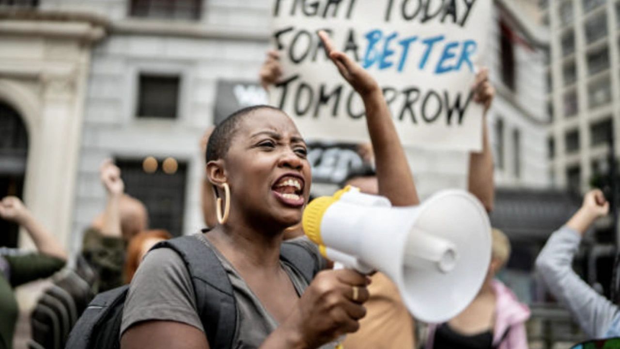 Black woman at protest shouting into a microphone
