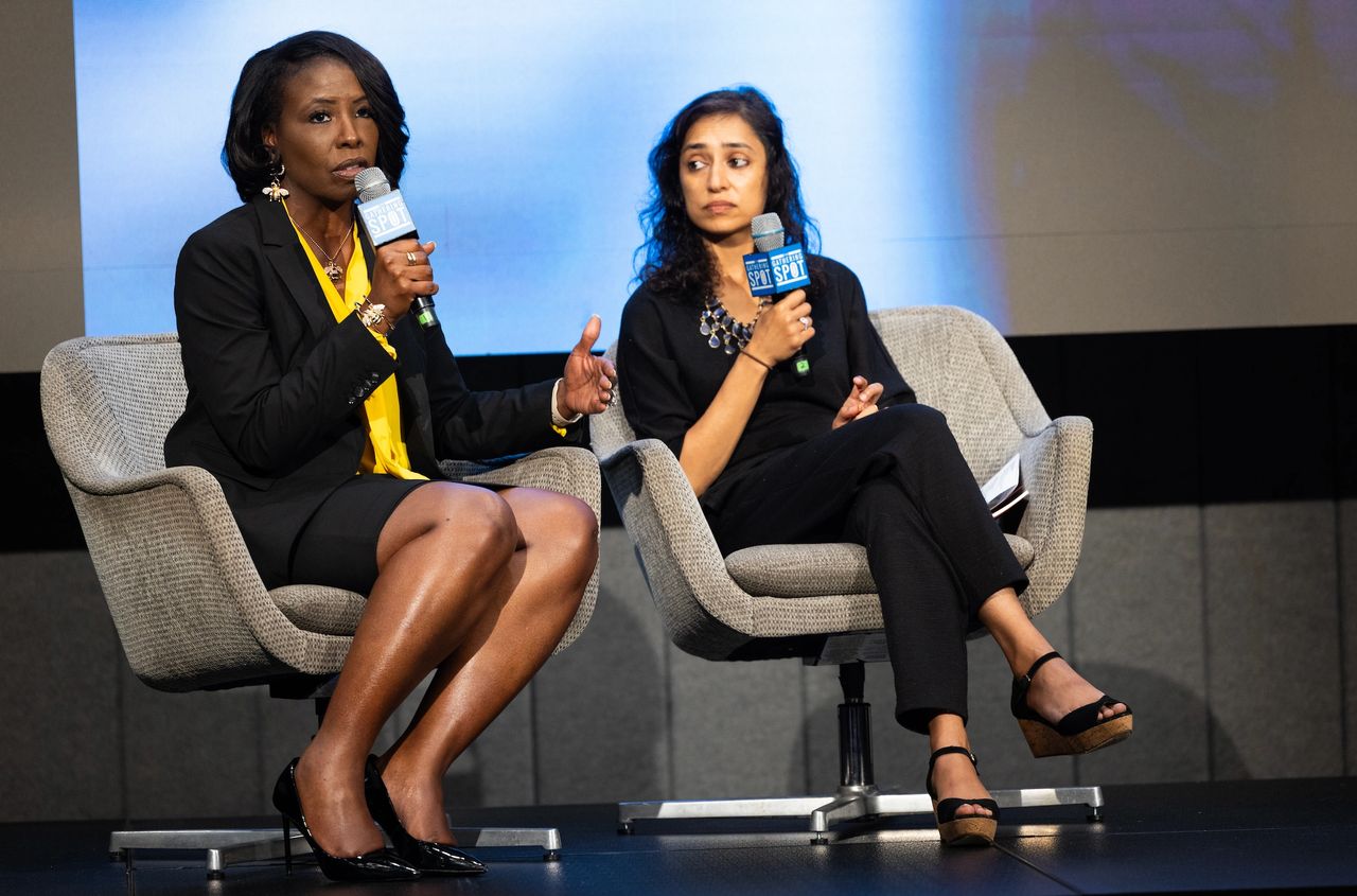 Two women on stage speaking with microphones.
