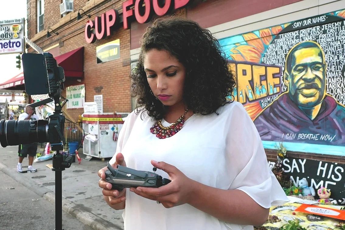 Georgia Fort in front of George Floyd mural. Black woman on an urban street looking at her camera