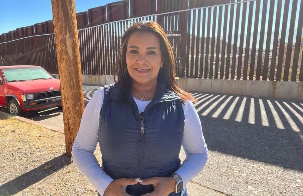 Latina woman in front of border wall