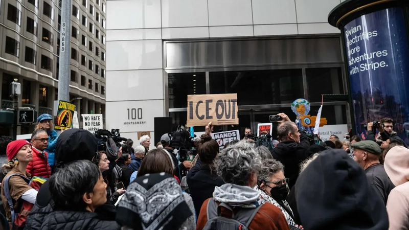 Group of people outdoors holding signs saying ICE OUT, No Hate, No Fear, etc.