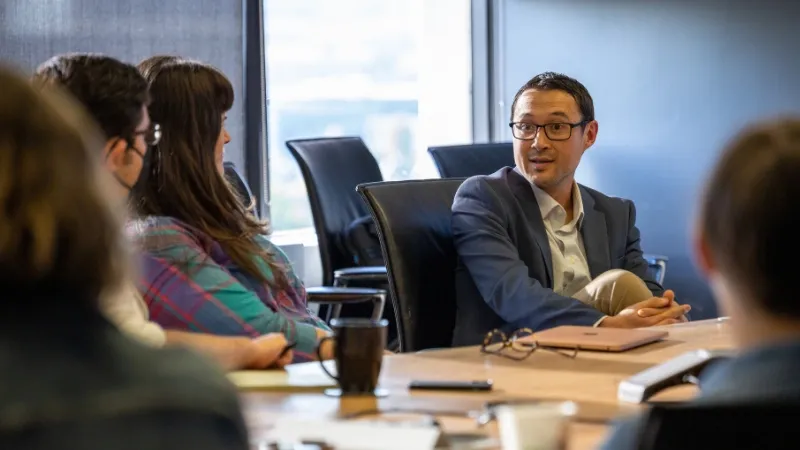 Journalists having a lively conversation around a conference room table.