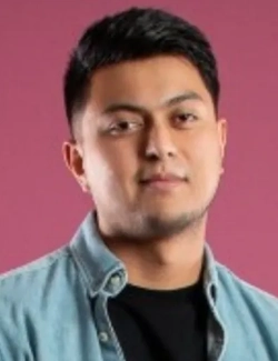 Young Latino man wearing a denim shirt with a half-smile.