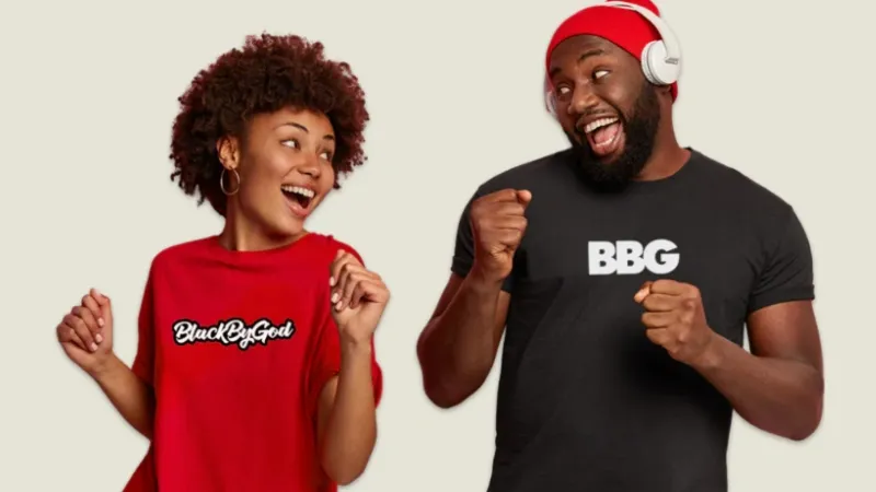 Black woman wearing a Black By God tshirt and a Black man wearing a BBG tshirt dancing and smiling at each other