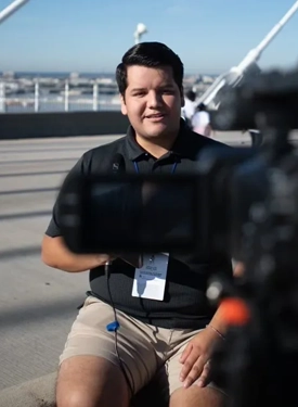 Male Latino reporter in the community reporting on events