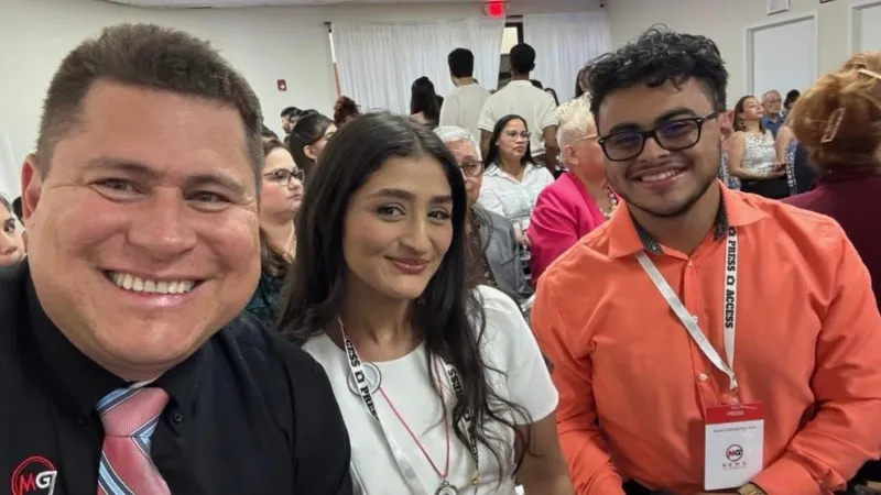 Two men and one woman smile together at an event