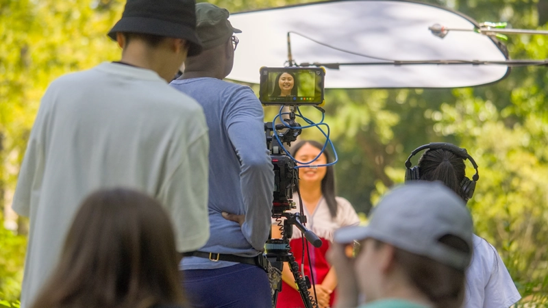 Six people filming an interview outdoors.