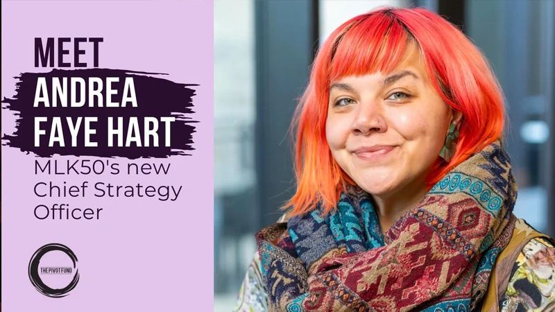Portrait of smiling Black woman with bright orange hair and a colorful scarf.