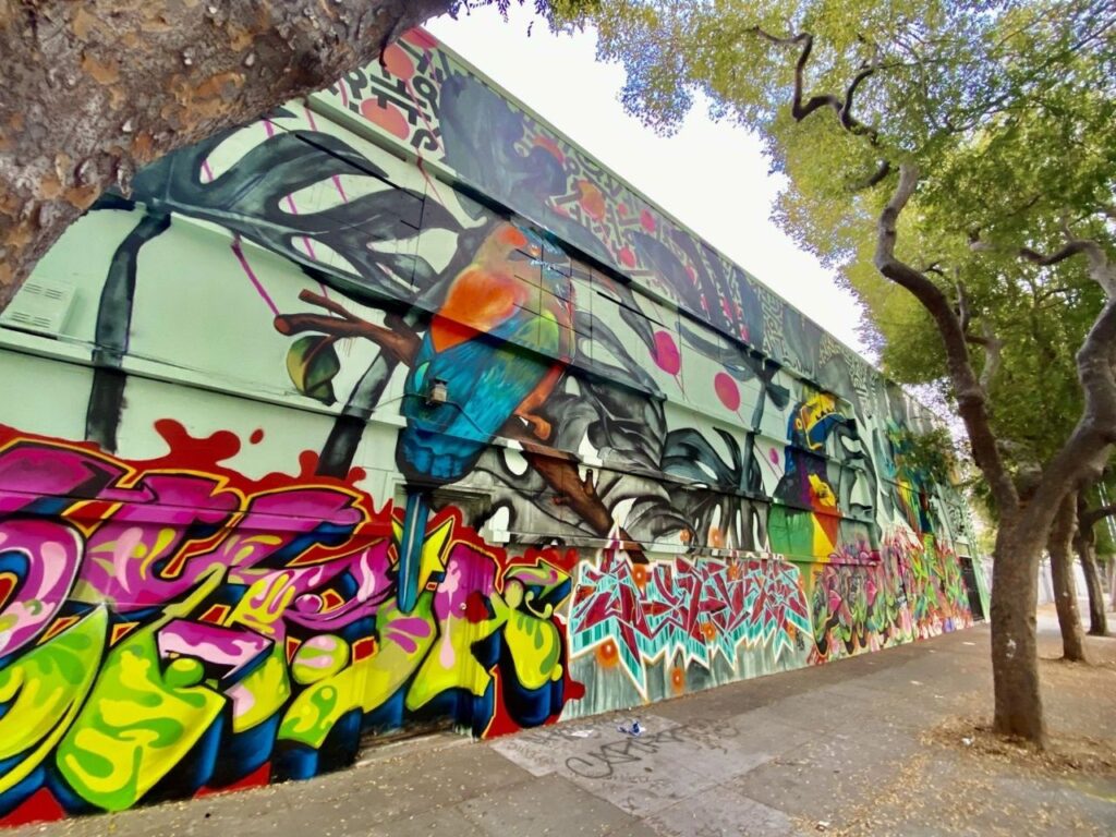 Art as story: Artists unveiled this mural on Folsom Street near 23rd Street in San Francisco's Mission District as an ode to the victims of gun violence and a reminder of the Mission’s culture of street art. Josué Rojas or ‘KID CEYBA’ is the former executive director of Acción Latina, and the mastermind behind the new mural. (Photo by Clara-Sophia Daly)