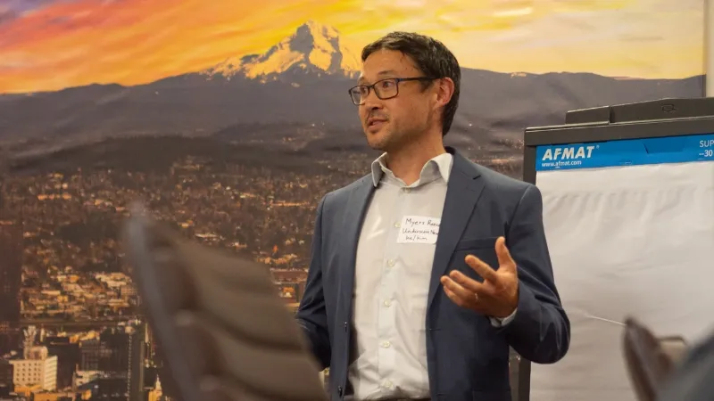 Man wearing buttondown shirt and jacket giving a presentation