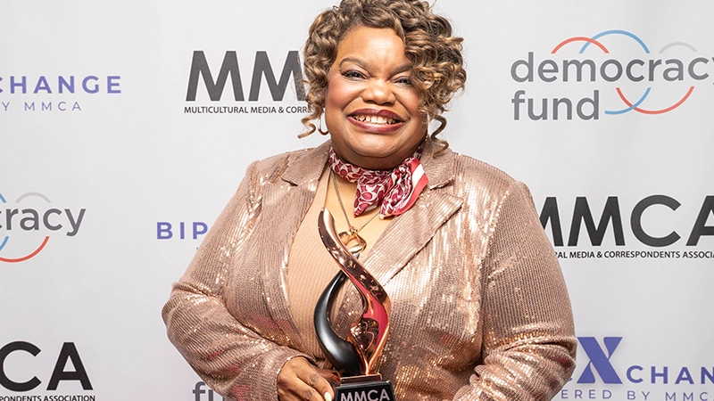 Tracie Powell in formal dress smiling and receiving an award