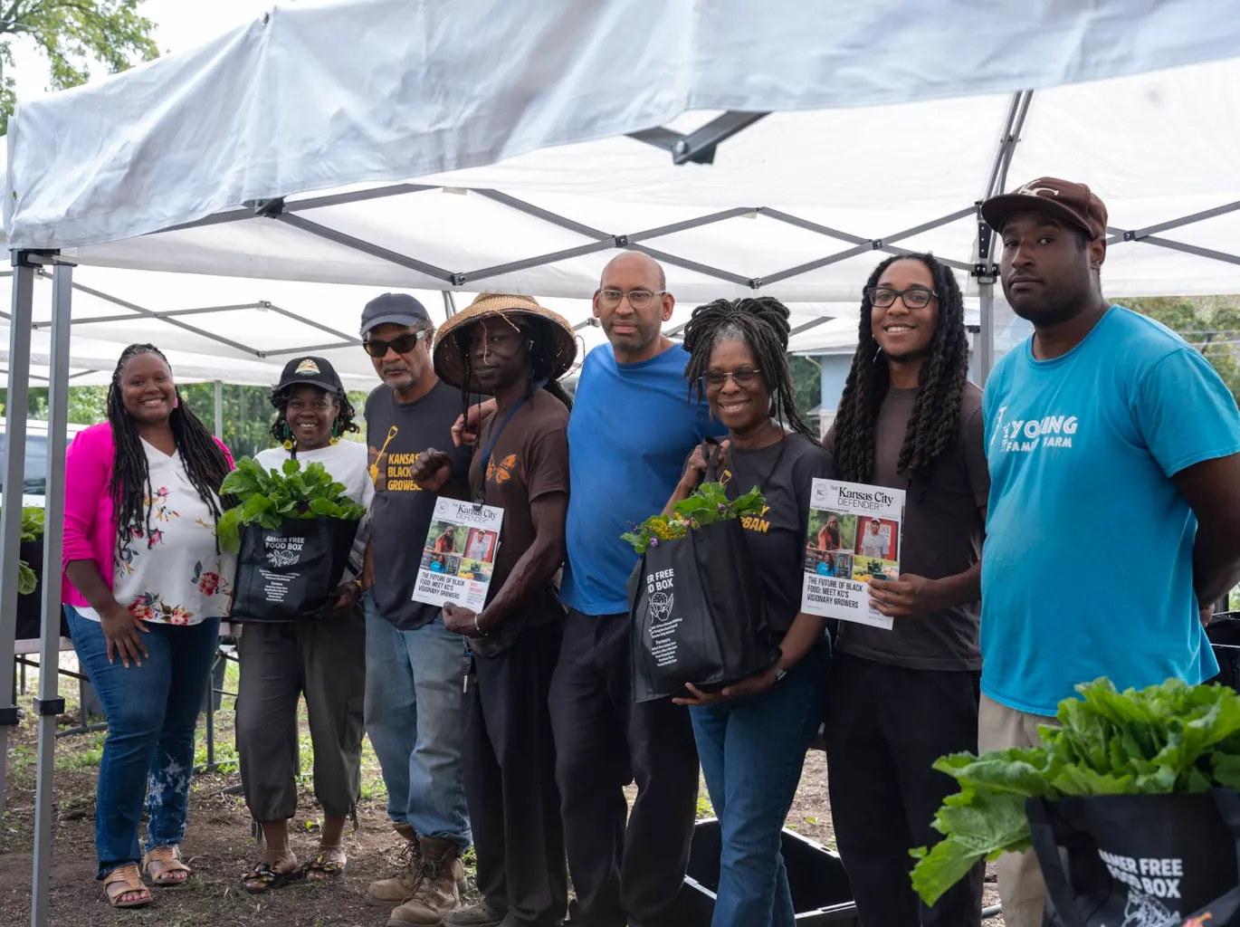 Food justice leaders hold Defender papers and bags of fresh food.