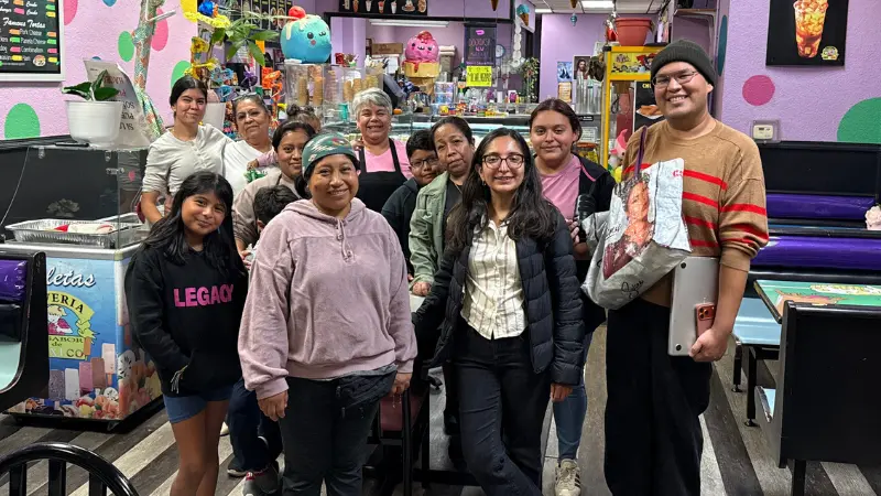 A group of Latino people pose for a photo inside of a restaurant.